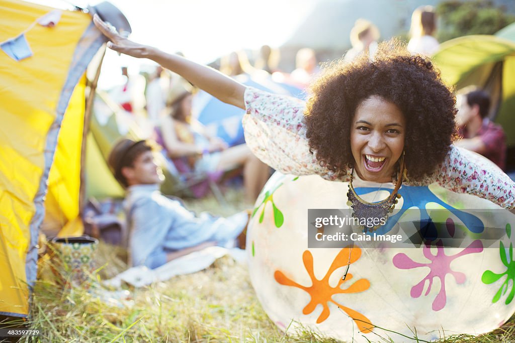 Portrait of playful woman laying on inflatable chair outside tents at music festival