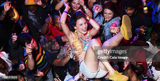 enthusiastic woman crowd surfing at music festival - crowdsurfing stock pictures, royalty-free photos & images