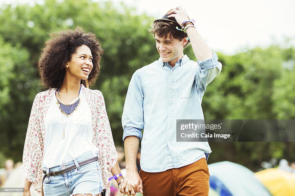 Couple holding hands outside tents at music festival