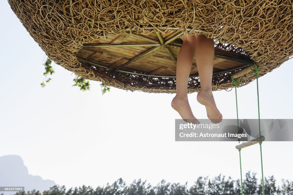 Pés dangling a mulher Ninho de Casa de Árvore