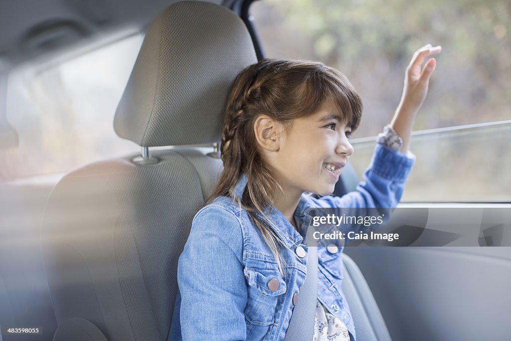 Heureuse fille colle main fenêtre de la voiture