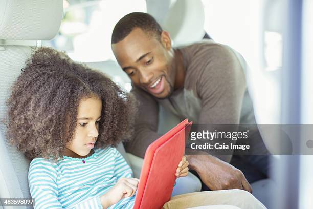 father and daughter using digital tablet in back seat of car - girls trip film stockfoto's en -beelden