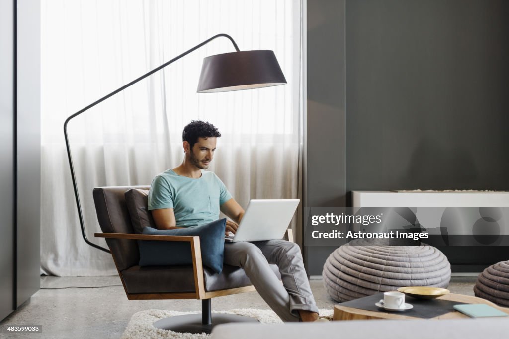 Mann mit laptop im Wohnzimmer