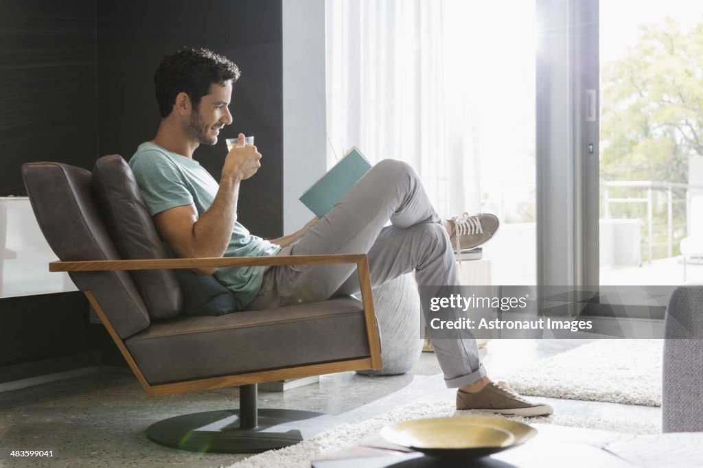 Homme de boire du thé et la lecture de livre dans la salle de séjour
