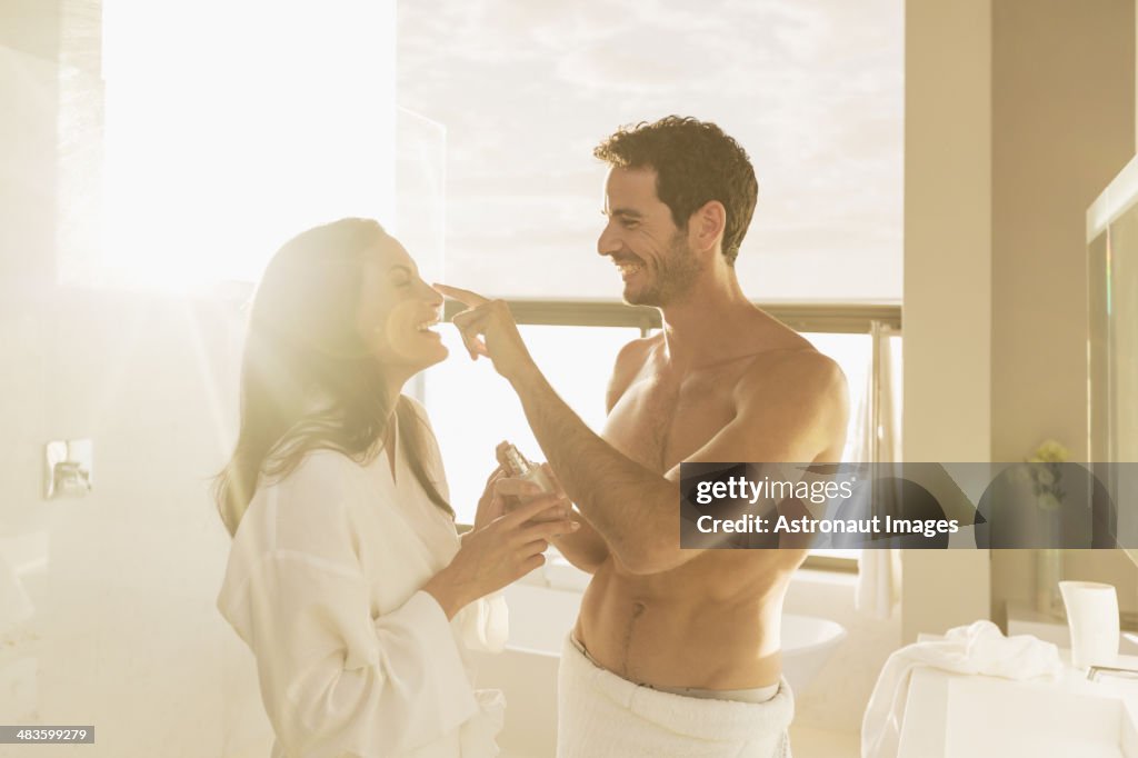 Couple playfully applying moisturizer in bathroom