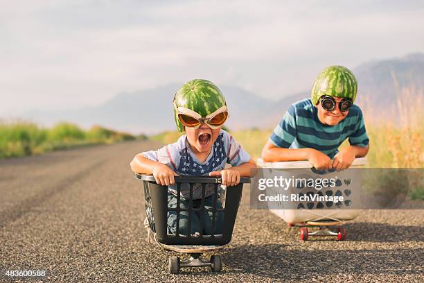 young boys racing wearing watermelon helmets - funny kids stock pictures, royalty-free photos & images