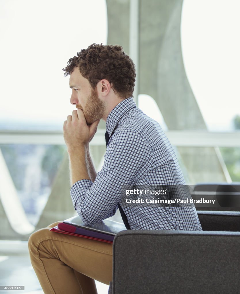 Pensive businessman sitting in office lobby