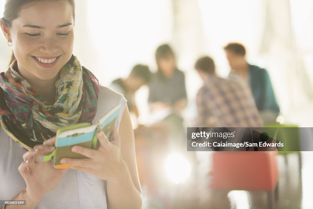 Happy businesswoman text messaging with cell phone outside meeting