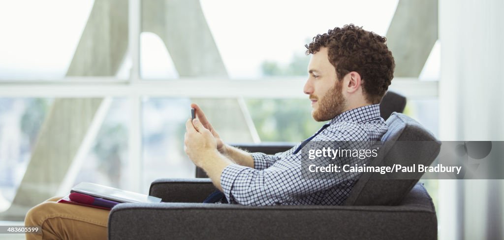 Homem de Negócios usando telefone celular no lobby