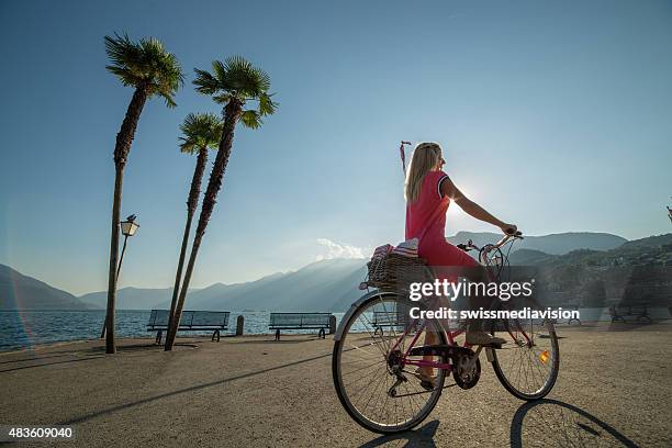 young woman on a bicycle at sunset - lake maggiore stock pictures, royalty-free photos & images