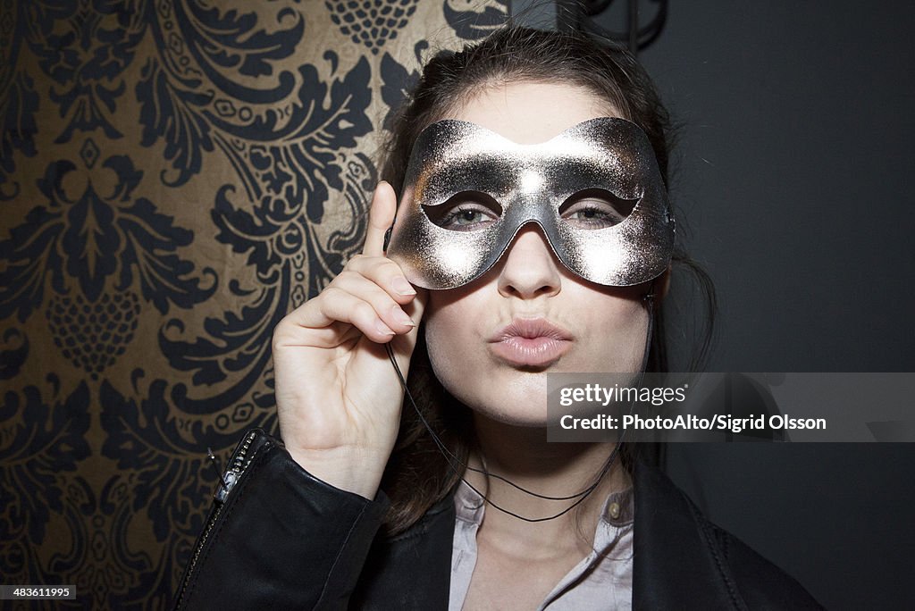 Woman wearing party mask, pursing lips, portrait