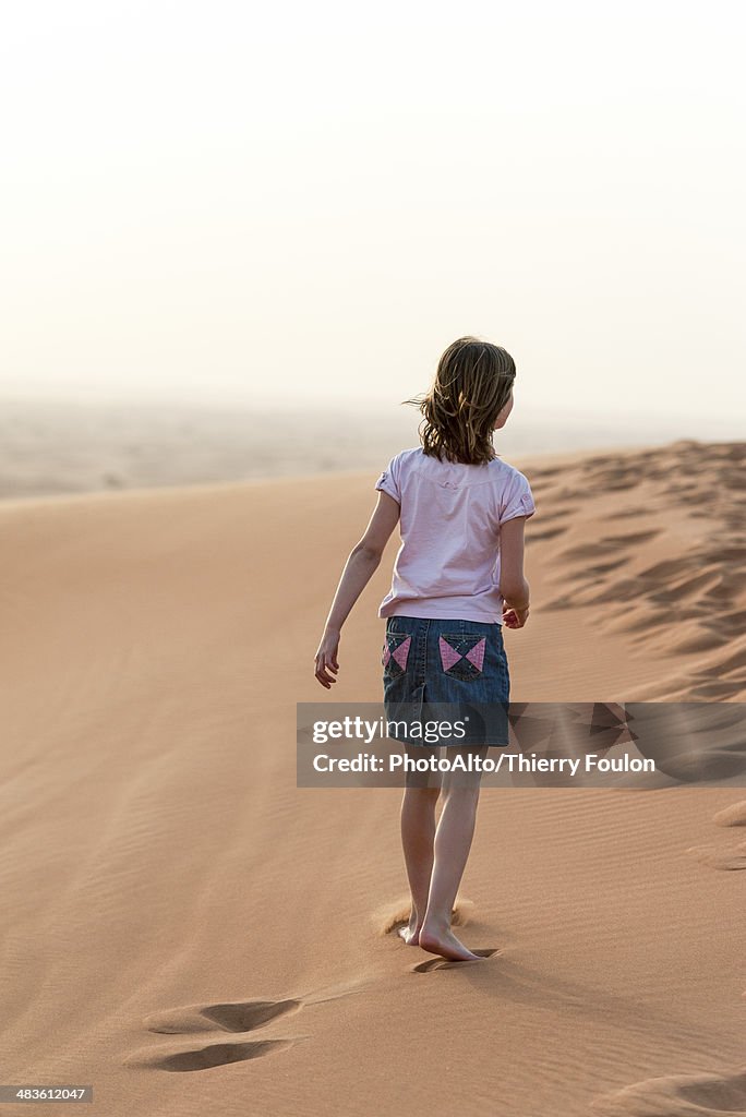 Girl walking in desert, rear view