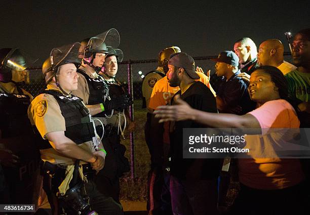 Demonstrators, marking the one-year anniversary of the shooting of Michael Brown, confront police during a protest along West Florrisant Street on...