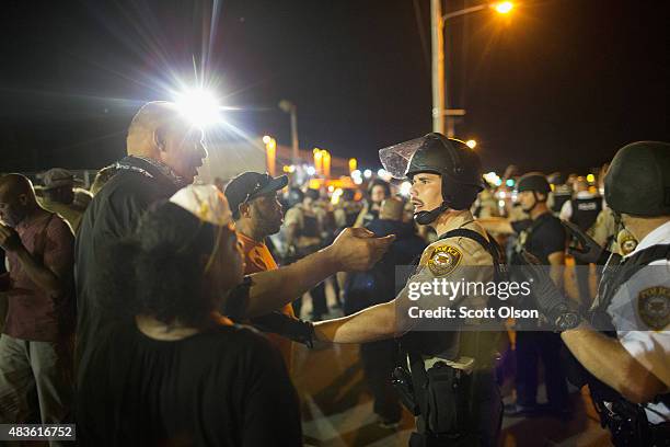 Demonstrators, marking the one-year anniversary of the shooting of Michael Brown, confront police during a protest along West Florrisant Street on...