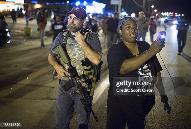 Demonstrator, marking the one-year anniversary of the shooting of Michael Brown, confronts a member of the Oath Keepers during a protest along West...