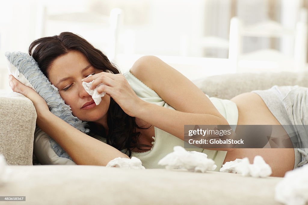 Pregnant woman crying on couch