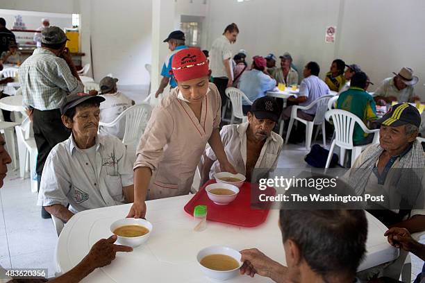 Karen Dicelis serves soup at the community eatery, El Mirador de los Abuelos, for lunch in the municipality of Muzo, department of Boyacá, Colombia,...