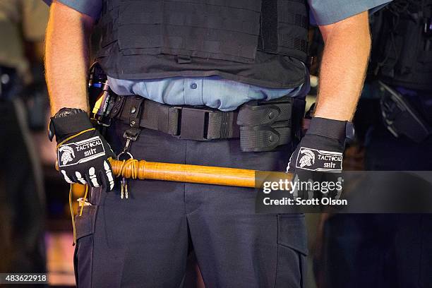 Police stand guard as demonstrators, marking the one-year anniversary of the shooting of Michael Brown, protest along West Florrisant Street on...