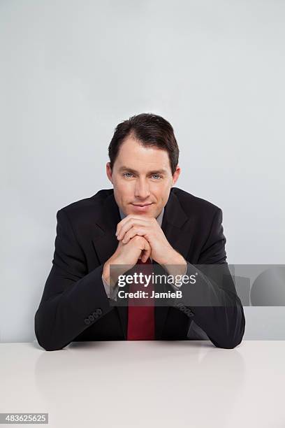 portrait of businessman sitting at table - hand on chin stock pictures, royalty-free photos & images