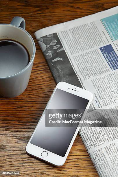An Apple iPhone 6 alongside a newspaper and cup of coffee, taken on October 3, 2014.