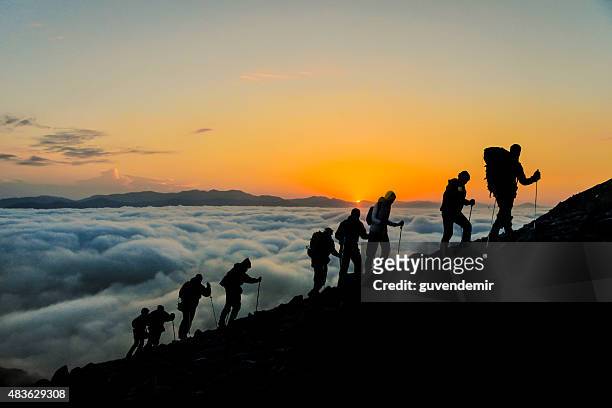 silhouettes of hikers at sunset - klättra bildbanksfoton och bilder