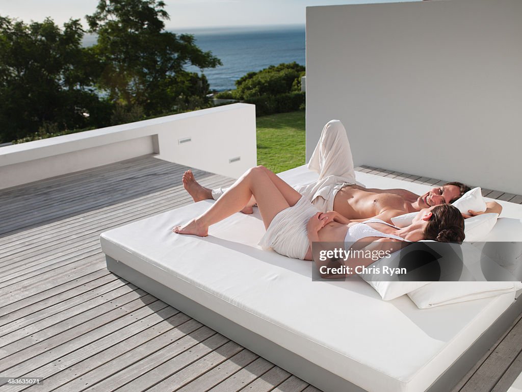 Man and woman lying down on bed outdoors 