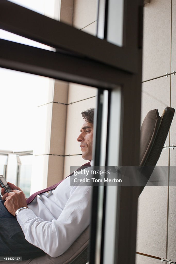 Businessman text messaging on balcony