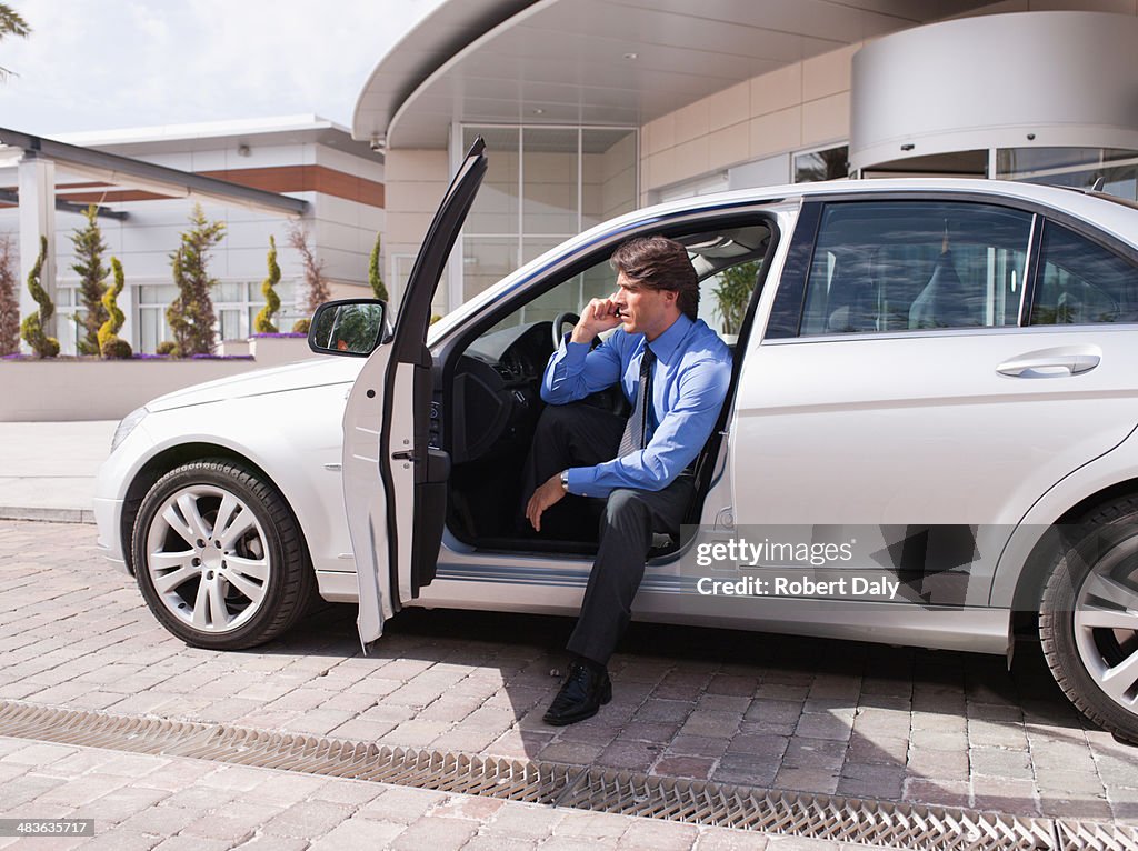 Businessman sitting in car talking on cell phone