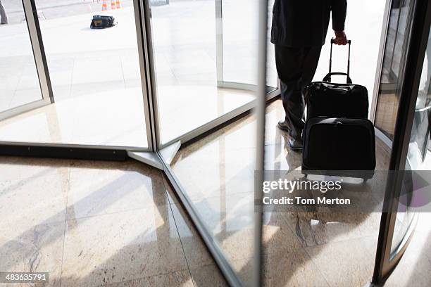 businessman with suitcase using revolving door - dichterbij komen stockfoto's en -beelden