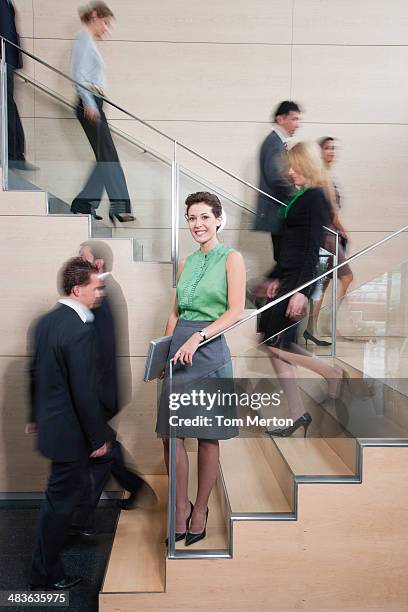 calm businesswoman in busy office staircase - tom chance stock pictures, royalty-free photos & images