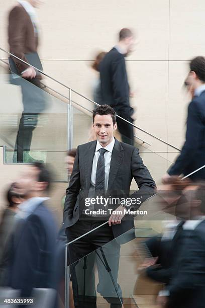 calm businessman in busy office staircase - tom chance stock pictures, royalty-free photos & images