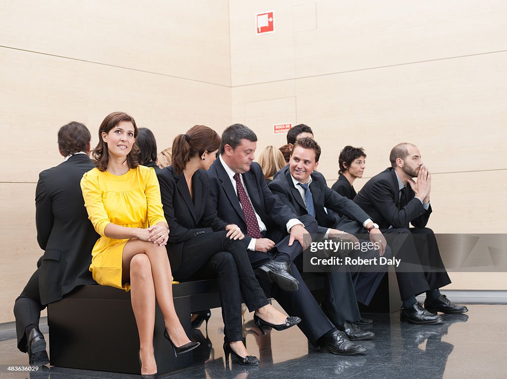 Businesspeople sitting on crowded bench