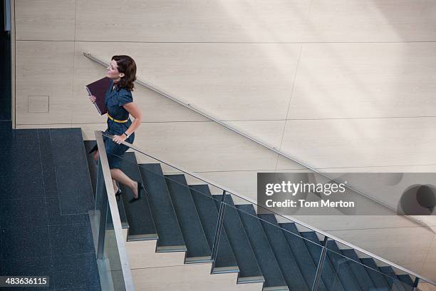 businesswoman ascending office staircase - stairs business stockfoto's en -beelden