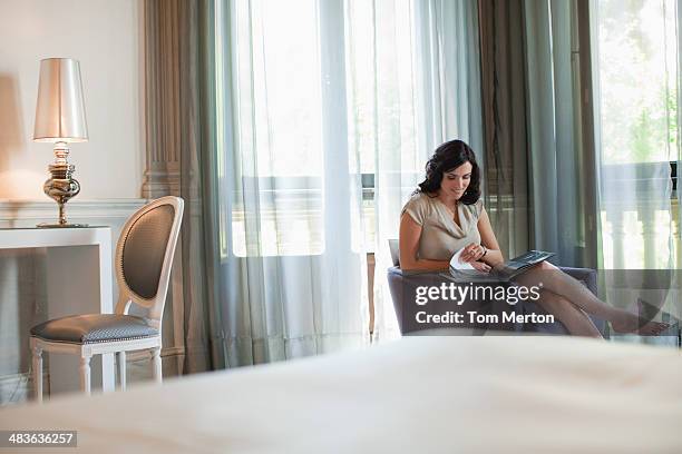 woman reading magazine in hotel room - newspaper luxury stockfoto's en -beelden