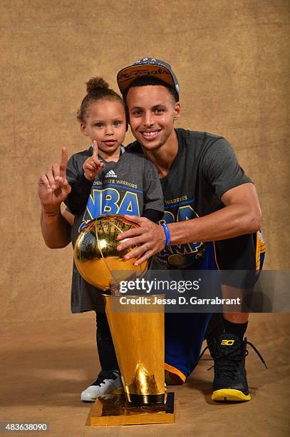 Riley Curry and Stephen Curry of the Golden State Warriors poses for a portrait with the Larry O'Brien trophy after defeating the Cleveland Cavaliers...