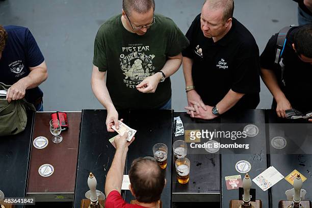 Customer pays for his beers with a 10 pound sterling banknote at the Great British Beer Festival in London, U.K., on Tuesday, Aug. 11, 2015. Europe...