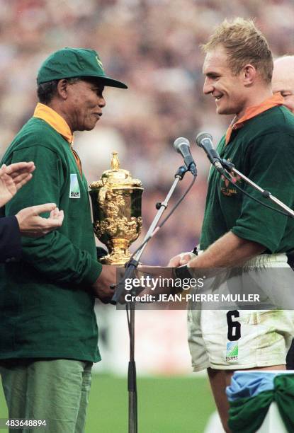 Le président sud-africain, Nelson Mandela, félicite le capitaine de l'équipe d'Afrique du Sud de rugby, François Pienaar, avant de lui remettre, le...