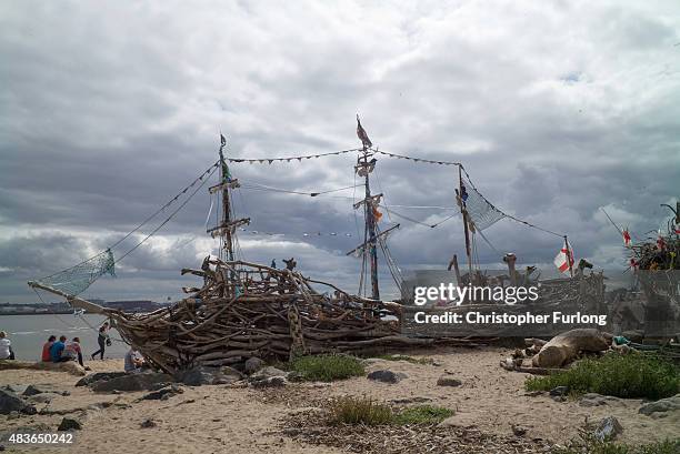 Daytrippers and children on the Summer break from school enjoy the Black Pearl pirate ship art installation, which is made from driftwood, at New...