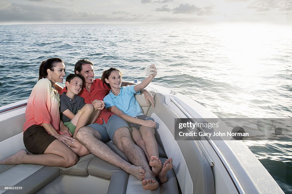 Family relaxing on motor boat, taking selfie