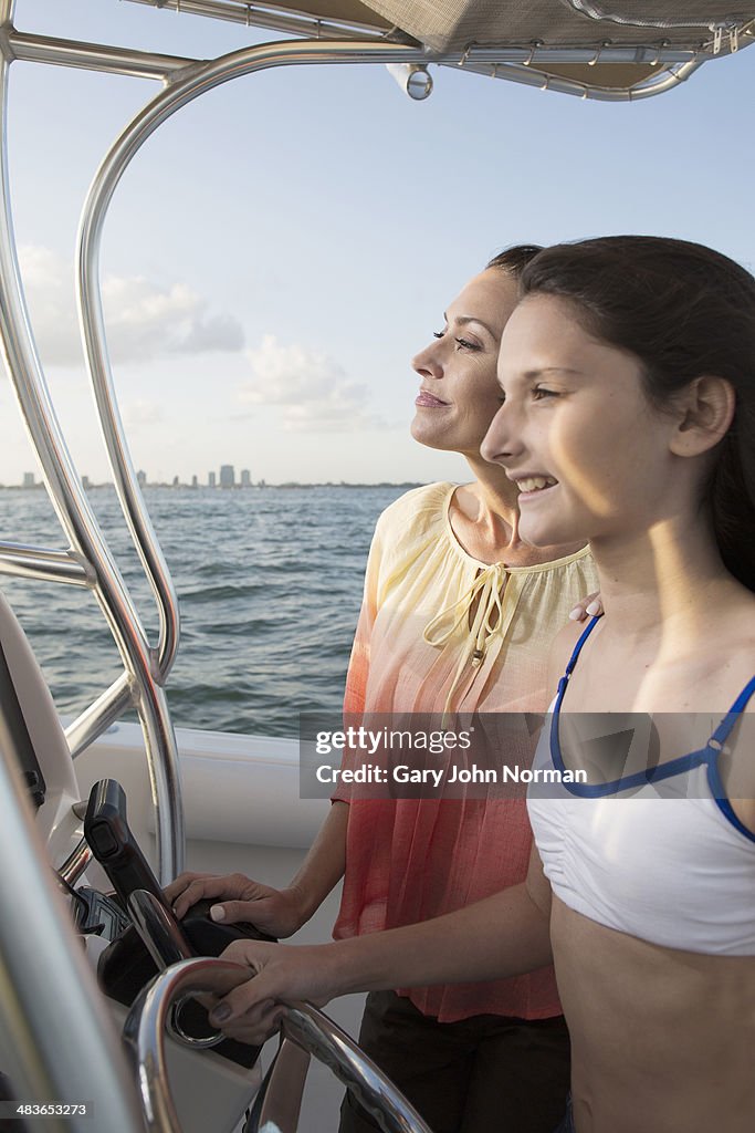 Young girl steers motor boat with mum