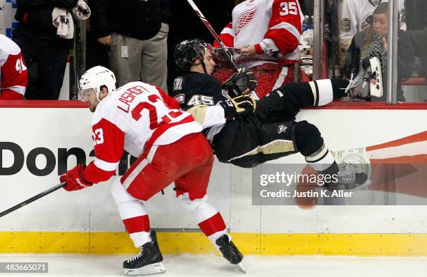Adam Payerl of the Pittsburgh Penguins is checked by Brian Lashoff of the Detroit Red Wings during the game at Consol Energy Center on April 9, 2014...