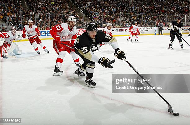 Beau Bennett of the Pittsburgh Penguins reaches for the loose puck in front of Brian Lashoff of the Detroit Red Wings on April 9, 2014 at Consol...