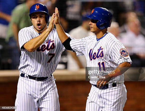 Travis d'Arnaud and Ruben Tejada of the New York Mets celebrate after they scored in the eighth inning against the Colorado Rockies on August 11,...