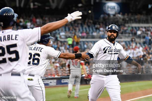 Matt Kemp of the San Diego Padres, right, is congratulated by Yangervis Solarte and Will Venable after scoring during the first inning of a baseball...