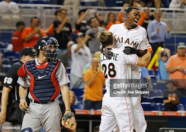Dee Gordon of the Miami Marlins celebrates his game-winning score with teammate Cole Gillespie of the Miami Marlins at home plate with Blake Swihart...
