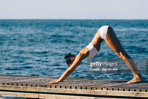 sportswoman practicing yoga at the quay - girl yoga stock pictures, royalty-free photos & images