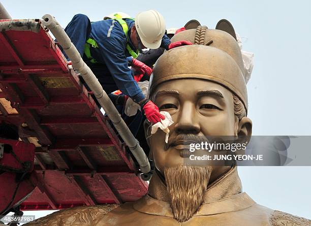 South Korean workers sweep the bronze statue of King Sejong, the 15th-century Korean King, during a street and park spring cleanup event at...