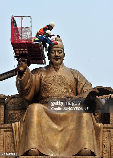 South Korean workers sweep the bronze statue of King Sejong, the 15th-century Korean King, during a street and park spring cleanup event at...