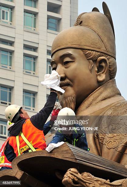 South Korean workers sweep the bronze statue of King Sejong, the 15th-century Korean King, during a street and park spring cleanup event at...