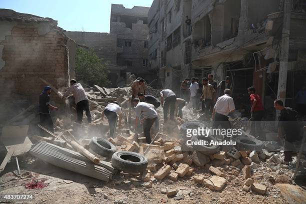 Syrian people conduct search and rescue works at the scene of a blast after Asad forces air strike at opposition controlled Hamuriye neighborhood in...